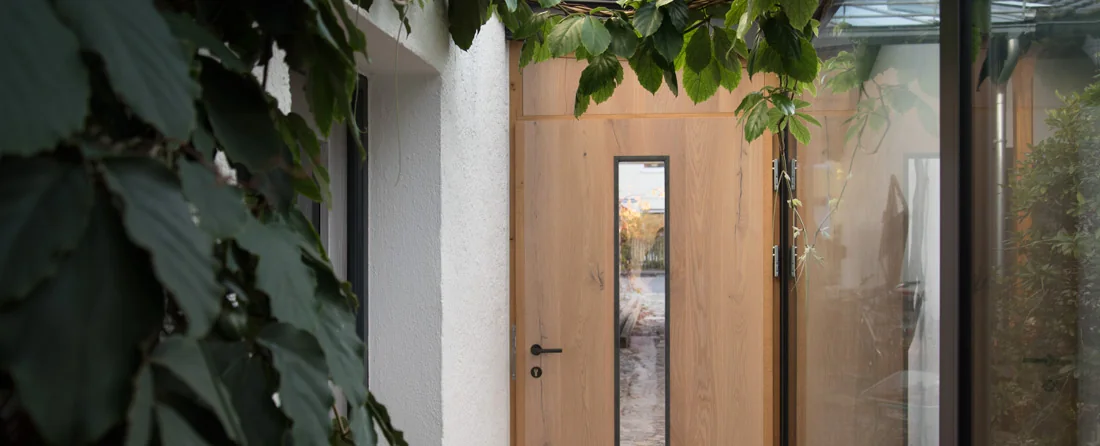 Individuell gefertigte Holztür mit schmalem Glaseinsatz in einem hellen Eingangsbereich
